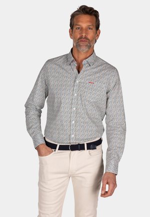 Overhemd met knoopsluiting van gestreepte blauwe, rode en witte stof. Lange mouwen, standaard kraag, gecombineerd met lichtgekleurde broeken en een donkere riem.