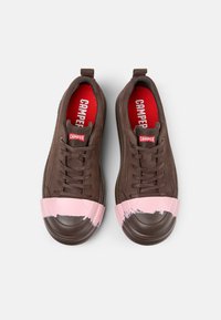Braune Schnürsneaker mit einem pinken Pinselstrich-Design auf der Zehenkappe. Mit rotem Fußbett und strukturiertem Gummisole.
