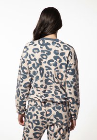 Beige sweatshirt met luipaardprint, voorzien van donkerblauwe en roze accenten. Gemaakt van zachte stof, met een ontspannen pasvorm en geribde manchetten.