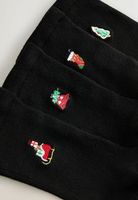 Schwarze Socken mit vier bestickten Feiertagsmotiven: einem Weihnachtsbaum, einem Strumpf, einem Auto mit Ornamenten und dem Weihnachtsmann im Schlitten.