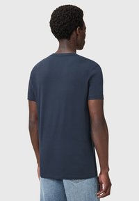 Námornícky modré bavlněné tričko s krátkým rukávem, kulatým výstřihem a hladkou texturou, zobrazené zezadu.