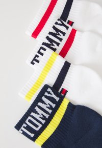 Baumwollsocken in Weiß und Marineblau, mit roten und gelben Streifen sowie "TOMMY"-Text an den Bündchen; gerippte Struktur, Knöchelhöhe.