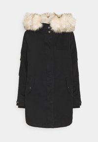 Svart parka-jacka med kunstpels huva. Har två sidofickor, en frontknäppning och en lapplåda på bröstet. Slät textur.