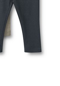 Tummanharmaat ribbileggingsit, joissa on tiukka muotoilu, elastinen vyötärö ja kontrastivärinen beige sisäpinta näkyvissä vyötärön kohdalla.