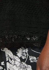 Renda preta com detalhes florais intrincados e designs em macramé, combinada com um tecido floral em preto e branco de contraste.