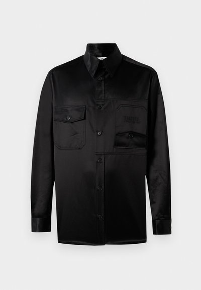 Μαύρο πουκάμισο με μακριά μανίκια, φτιαγμένο από απαλό ύφασμα. Διαθέτει πιεσμένο γιακά, κλείσιμο με κουμπιά μπροστά και δύο τσέπες στο στήθος με καπάκι.