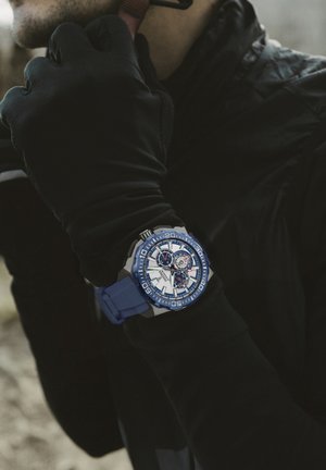 Montre avec bracelet en silicone bleu, boîtier en argent, cadran blanc et accents bleus ; elle dispose de trois sous-cadrans et d'index horaires audacieux.