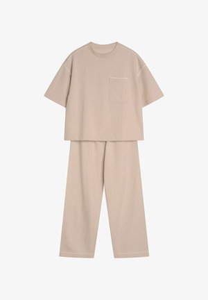 Beżowy bawełniany zestaw dwuczęściowy składający się z topu z krótkim rękawem z kieszonką na piersi oraz spodni z szerokimi nogawkami, oba z delikatnym kontrastowym szwem.
