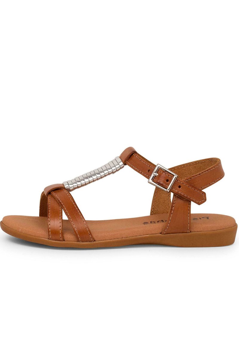 Brown leather sandals with a flat sole, featuring a decorative metallic accent and adjustable ankle strap. Detailed crisscross design.