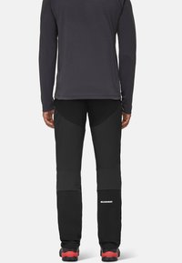 Zwarte softshell broek met textuur, met een slim fit en logo detail op het onderbeen. Strakke tailleband en gewatteerd kniekontuur.