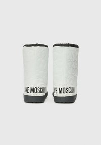 Witte gewatteerde laarzen met een zwart gewatteerde kraag en een contrasterende zwarte zool. Bevat het "LOVE MOSCHINO" logo in bold op de hak.