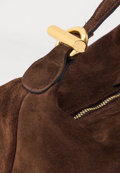 Brown suede handbag featuring a gold-tone hardware clasp and zipper, emphasizing a soft texture and a rounded shape.