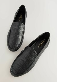 Zwarte instappers met een leren bovenwerk met een gestructureerd krokodillenpatroon. Slip-on ontwerp met een gepolsterde binnenzool en stiksels langs de randen.