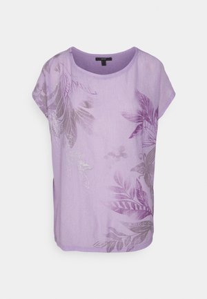 Blouse lavande à manches courtes avec un col rond, présentant un motif floral et feuillage subtil en pourpre foncé avec des accents argentés.