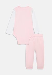Bodysuit de algodão rosa claro com mangas longas brancas e calças combinando com cinta elástica e tornozelos lembrados.