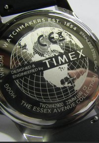 Le fond de boîte de la montre Timex présente un design en acier inoxydable avec un graphique de globe, un marquage CE et des inscriptions détaillant le modèle et les informations de collection.
