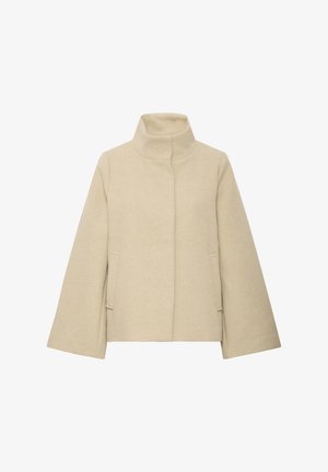 Veste en laine beige avec col montant, manches longues et larges, fermeture frontale cachée et deux poches latérales.