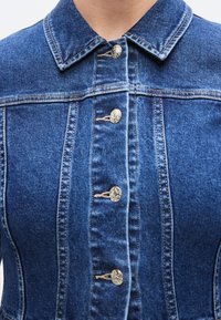 Φόρεμα από τζιν με γιακά, κλείσιμο μπροστά με κουμπιά σε ασημένιο τόνο και δομημένες ραφές. Σκούρο μπλε ύφασμα με λεία υφή.