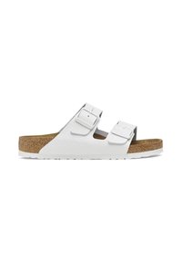 Sandales à glissière blanches à deux boucles avec un dessus en synthétique texturé, un pied de liège et une semelle extérieure en caoutchouc blanc. Design minimaliste avec des straps ajustables.