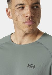 Grijze, geribbelde shirt met korte mouwen en een ronde halslijn, met een zwart logo, zichtbaar stikwerk en een gestructureerde stofafwerking.