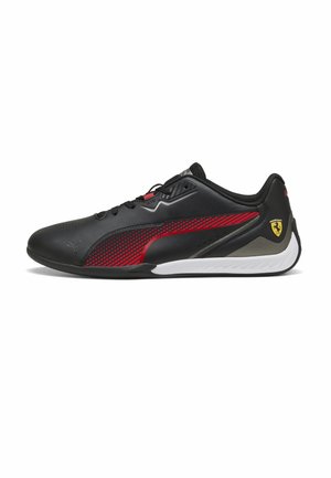 Baskets basses noires avec bande latérale rouge, lacets noirs, semelle blanche et logo Ferrari jaune au talon, vues de côté.