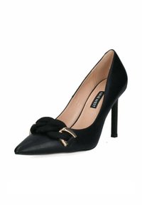 Scarpa nera in pelle con tacco alto e punta affusolata, caratterizzata da una corda nera annodata e un accento in metallo dorato sulla parte frontale.