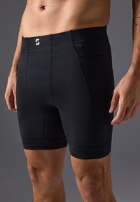 Black athletic shorts with a fitted design, made of stretchy fabric, featuring side pockets and contrasting seams.