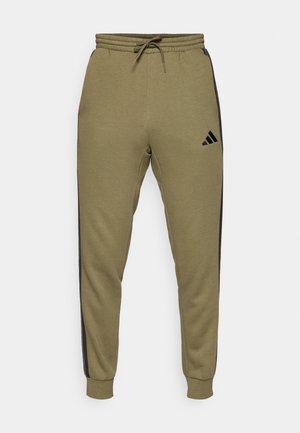 Pantaloni jogger verde oliva realizzati in tessuto morbido, con strisce laterali nere, vita elastica con cordino e polsini a costine. Logo Adidas sulla coscia.