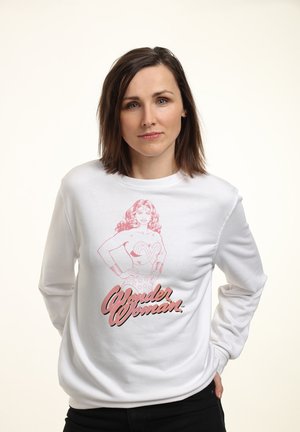 Biała bluza z długim rękawem, z różową grafiką przedstawiającą Wonder Woman i napisem "Wonder Woman". Okrągły dekolt, materiał bawełniany.