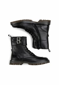 Botas de cuero negras hasta el tobillo con una suela gruesa, parte delantera con cordones y cierre lateral. Presentan un acento de hebilla en el puño y un acabado texturizado.
