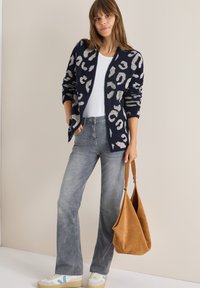 Námorníkový cardigan s šedým leopardím vzorem, kombinovaný se světle šedými džíny a hnědou semišovou kabelkou. Bílé tenisky s modrými akcenty.