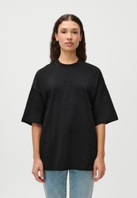 Sort oversized t-shirt lavet af bomuld. Har rund hals og korte ærmer med "LeGen" logo prægede foran.