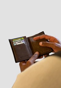 Brown leather wallet opened to reveal card slots. Features a textured interior, with embossed "SERASAR" logo on the front and multiple cards visible.