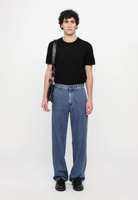Black short-sleeve t-shirt, light blue denim jeans, plain design, relaxed fit, paired with black shoes and a small black crossbody bag.