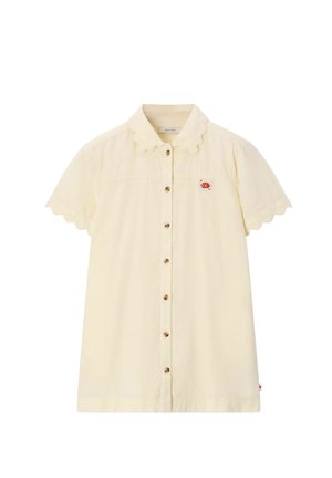 Chemise crème à manches courtes boutonnée, avec des bords festonnés sur le col et les manches, et un petit patch poisson rouge sur la poitrine.
