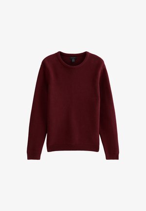 Suéter de punto burdeos con cuello redondo, mangas largas y dobladillo acanalado. Tejido texturizado con un corte clásico y sin detalles adicionales.