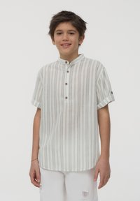 Camicia a maniche corte con bottoni, di colore bianco con strisce verticali grigie. Presenta un colletto alla cinese e polsini arrotolati. Tessuto morbido.
