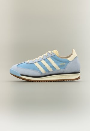 Ανοιχτό γαλάζιο παπούτσι Adidas SL 72 με εκρού ρίγες, επενδύσεις από σουέτ, εκρού κορδόνια και καφέ ραβδωτή σόλα, εμφανιζόμενο από το πλάι σε ουδέτερο φόντο.