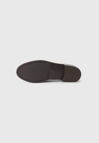 Black leather shoe sole with a smooth finish, slightly rounded toe, and minimal stitching details along the edge. Flat and textured surface.