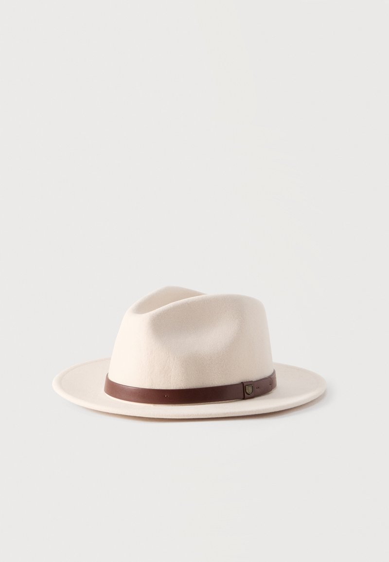 Sombrero fedora de ala ancha color crema con una banda de cuero marrón y un pequeño detalle de hebilla, exhibido sobre un fondo blanco liso.