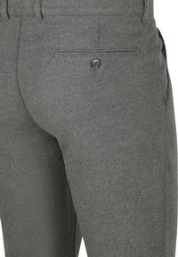 Grijze wollen broek met een rechte snit, achterzak met knoopsluiting en subtiele textuurafwerking. Minimalistische ontwerpelementen aanwezig.