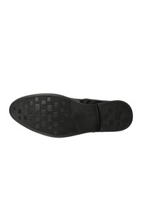Sole di scarpa nera con superficie in gomma texturizzata, caratterizzata da un motivo a griglia e branding. Design piatto senza tacchi visibili o decorazioni.