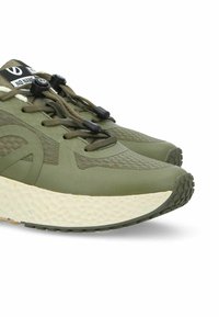 Baskets de sport vertes avec un dessus en mesh texturé, des lacets élastiques et une semelle épaisse à pois blancs. Bout arrondi et semelle en caoutchouc pour une meilleure adhérence.