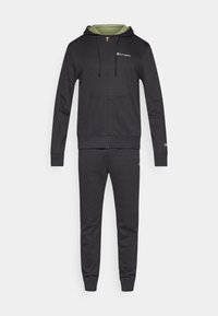 Μαύρο φούτερ με φερμουάρ, πράσινη επένδυση εσωτερικά και λογότυπο στο στήθος, σε συνδυασμό με μαύρο παντελόνι φόρμας που ταιριάζει. Λείο ύφασμα, casual σχεδίαση, ελαστικές μανσέτες.