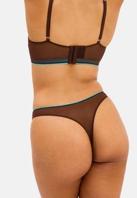 Bra und Tanga-Set aus braunem Mesh mit verstellbaren Trägern und einem türkisfarbenen Akzent, das eine glatte Textur und ein minimalistisches Design hervorhebt.
