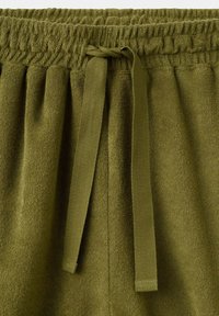 Olivengrønne frottébukser med elastisk taljebånd og bundet fladt stofsnor foran i midten.
