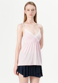 Pink cotton camisole with lace trim at the neckline, featuring thin straps and a flowy design, paired with a dark layered ruffle skirt.
