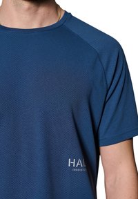 Marinblå atletisk T-shirt med andningsbar mesh-textur, rundad halsringning och texten "HAL 19681978" i ljusgrått på framsidan.