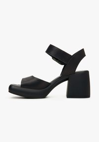 Zwarte blokhak sandalen van glad materiaal, met twee banden: één over de tenen en één rond de enkel, met een ronde neus.