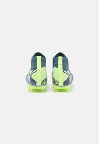 Soccer cleats with a textured dark blue upper, lime green accents, and a patterned design. Features a high-top collar and molded studs.